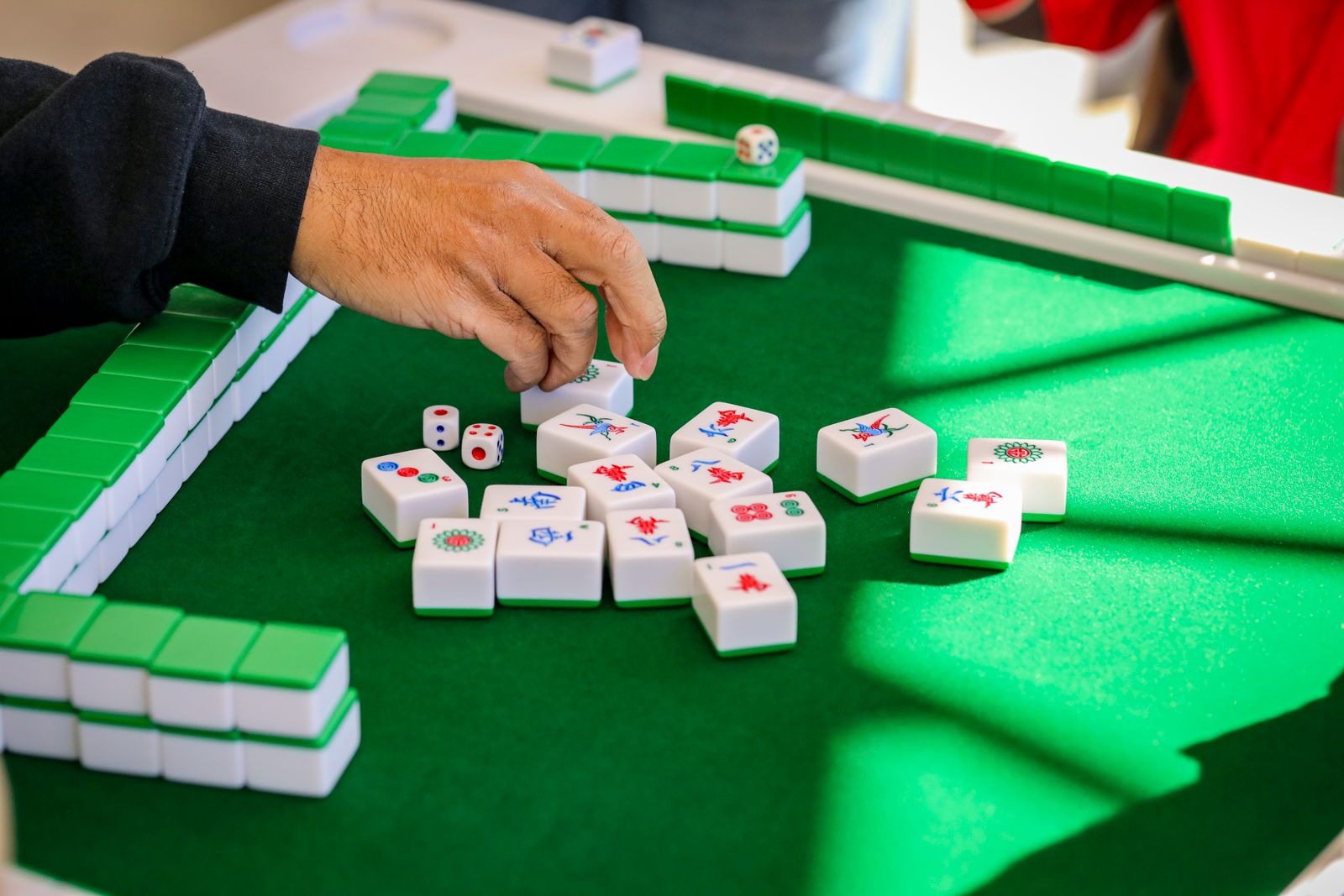 Hands arranging mahjong tiles during an intense game