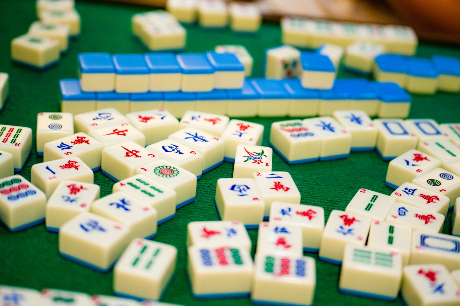Colorful mahjong tiles laid out on a green felt table